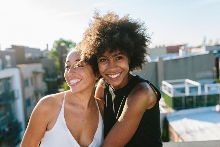 Mixed race same sex female couple, embracing and smiling in the sun