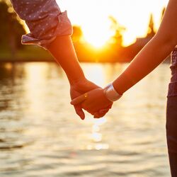 Couple holding hands next to river