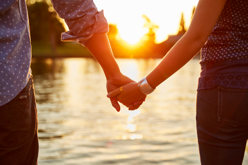 Couple holding hands next to river