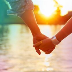 Two people holding hands with sunset