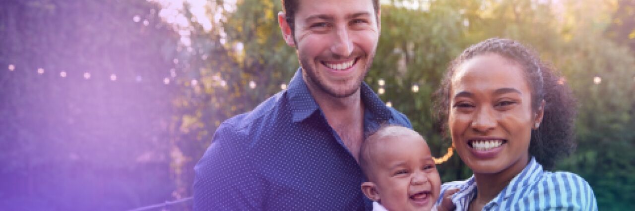 Man and woman smiling holding a baby