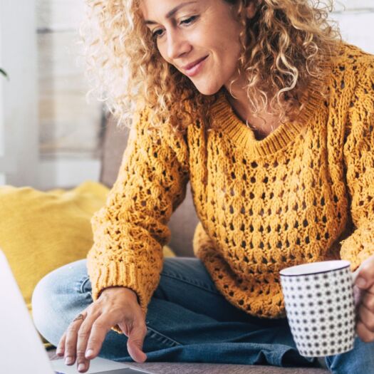 Blonde woman sitting down using her laptop with a mug 