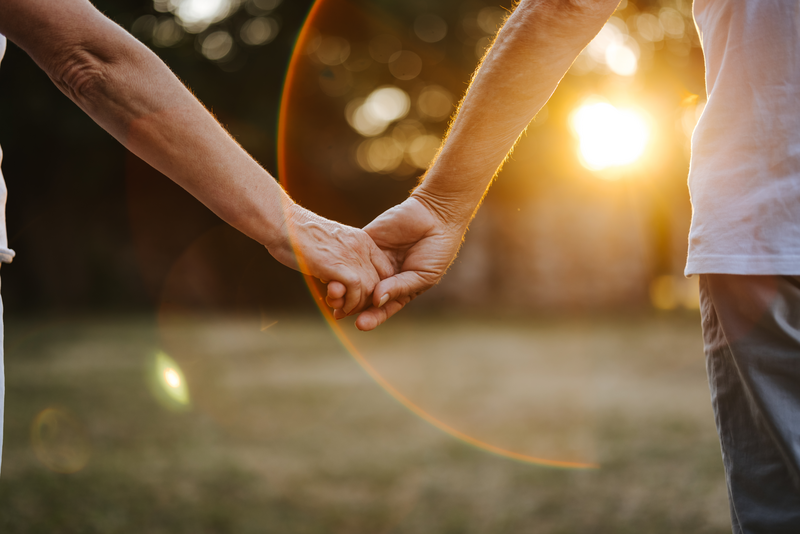 Close-up shot of  couple holding hands in nature at sunset