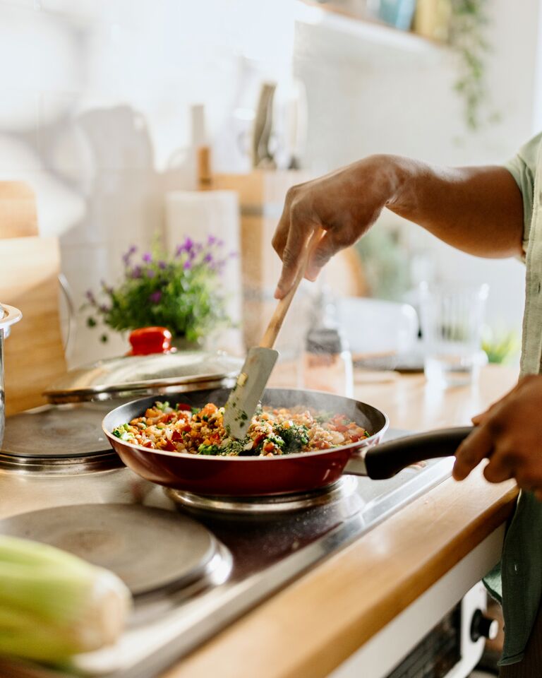 Woman preparing quinoa vegetable mix cooked in a frying pan