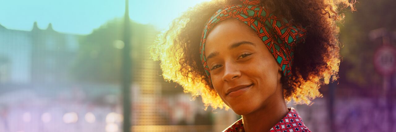 Close up of single black woman with curly hair smiling at camera 