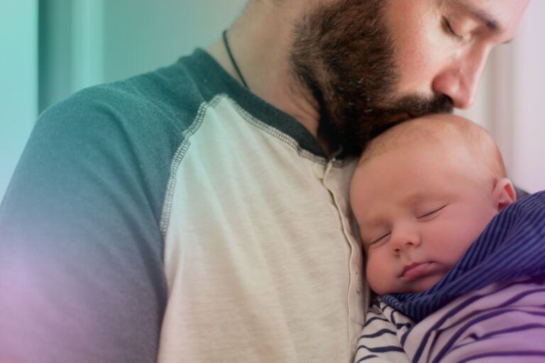 Bearded man holding baby and kissing top of head
