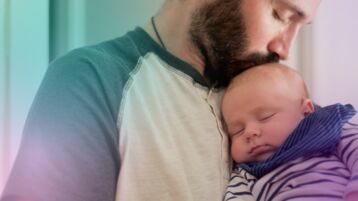 Bearded man holding baby and kissing top of head