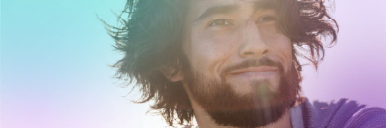 Close up of man with mid-length brown hair and beard, smiling