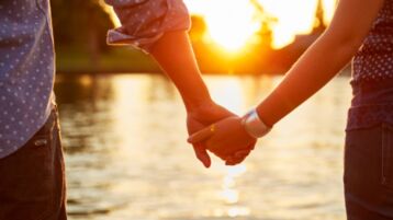 Two people holding hands with sunset