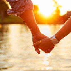 Two people holding hands with sunset