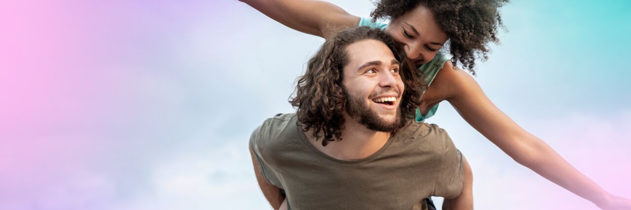 A white man pig backing a black woman, the man is smiling and she is looking at him.