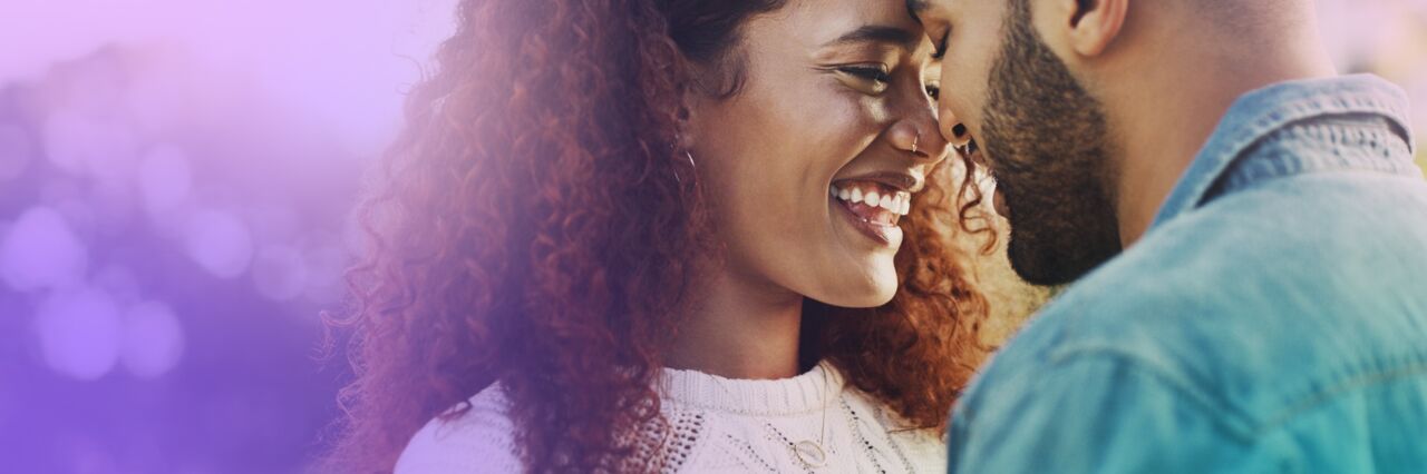 Black heterosexual couple,  laughing close together.