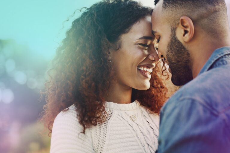 Black heterosexual couple,  laughing close together.