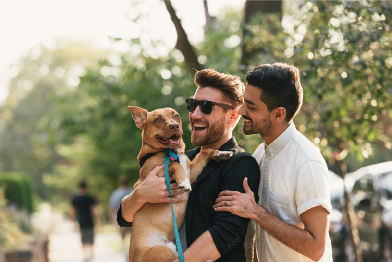 Same sex male couple smiling with their dog