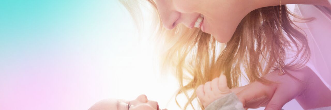 mother and baby laughing whilst baby is lying on back 